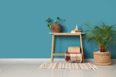 Kitaplı masa ve mavi duvarın yanındaki çiçekli oda.