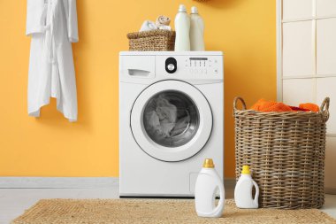 Modern çamaşır makinesi, hasır sepeti ve deterjan şişeleriyle şık bir çamaşır odası.