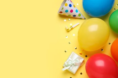 Farklı hava balonlarıyla kompozisyon, hediye kutuları ve sarı arka planda konfeti, yakın plan.