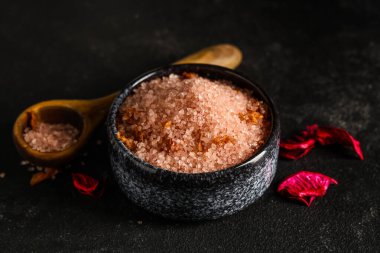 Siyah arka planda deniz tuzu ve taç yapraklarıyla kaplıcada güzel bir kompozisyon, yakın plan.