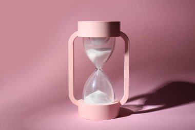 Pembe arka planda kristal kum saati