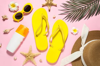 Şık plaj ayakkabıları, bir şişe güneş kremi ve pembe arka planda aksesuarları olan kompozisyon, yakın plan.