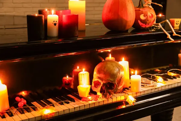 Büyük piyano, yanan mumlar ve karanlık odada Cadılar Bayramı dekoru.
