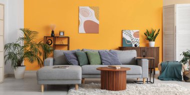 Sarı duvarın yanında rahat bir kanepe ve kahve masası olan oturma odasının içinde.