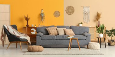 Rahat gri kanepe, puf ve masa aydınlık oturma odasının içinde.