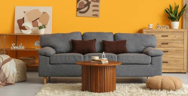 Oturma odasının içinde rahat bir kanepe, masa ve puf.