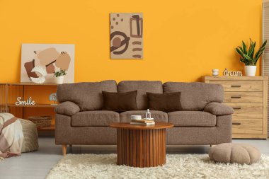 Oturma odasının içinde rahat bir kanepe, masa ve puf.