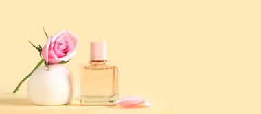 Bir şişe parfüm ve sarı arka planda güzel güllü dekoratif podyum.
