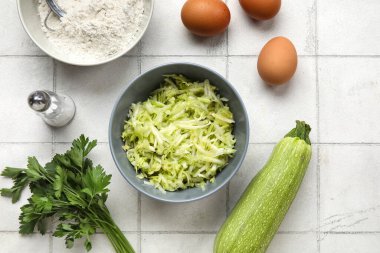 Beyaz fayanslı börek hazırlamak için rendelenmiş kabak, un ve yumurta kâseleri.