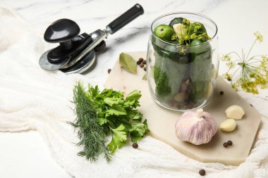 Beyaz mermer arka planda korunması için taze salatalıklı kavanoz.