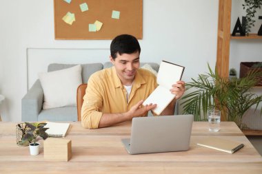 Not defteri olan genç bir adam evde iş görüşmesi yapıyor.