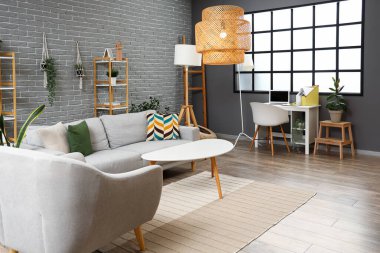 Gri kanepesi, koltuğu, sehpası ve lambası olan oturma odasının içinde.