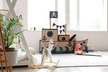 Çocuk odasında oyuncakları olan korsan karton gemi.