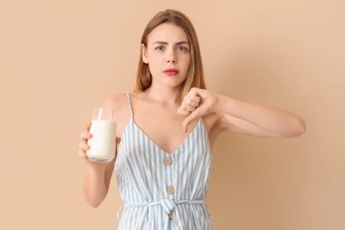 Laktoz toleransı olmayan genç bir kadın bej arka planda baş parmak izini gösteriyor.