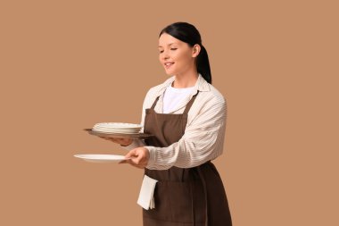 Kahverengi arka planda tepsisi ve tabağı olan güzel bir garson kız.