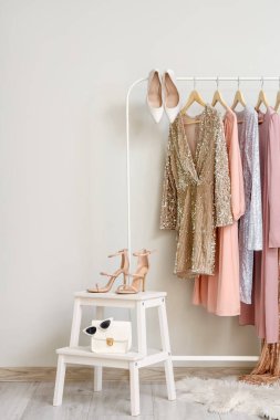 Beyaz duvarın yanında şık elbiseler ve şık topuklu ayakkabılar.