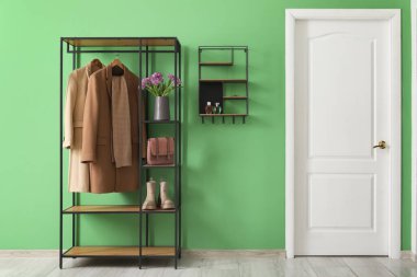 Elbise askılığı, raf ve bahar çiçekleriyle süslü bir koridor.