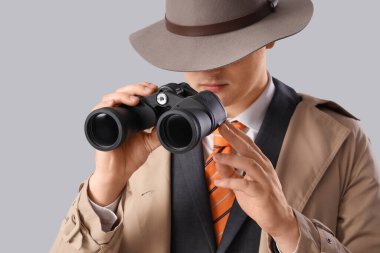 Erkek casus, arka plandaki dürbünle bakıyor, yakın plan.