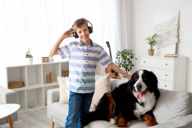 Evde Bernese dağ köpeğiyle kulaklık takan küçük çocuk.