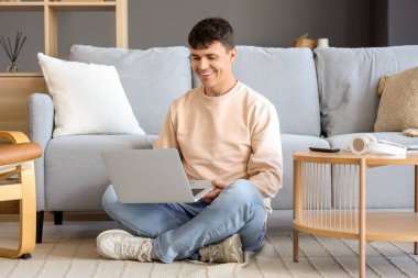 Katta evde dizüstü bilgisayar kullanan genç adam