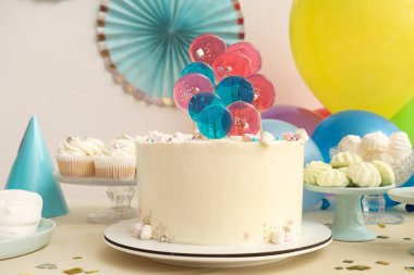 Beyaz duvara karşı pasta, şeker ve doğum günü partisi için dekorasyon masası.