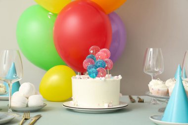 Beyaz duvara karşı pasta, şeker ve doğum günü partisi için dekorasyon masası.