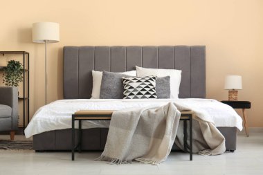 Güzel yatak odasında rahat bir yatak, lamba ve komodin.