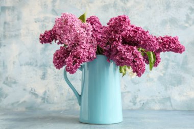 Açık mavi arkaplanda çiçek açan bir sürahi.