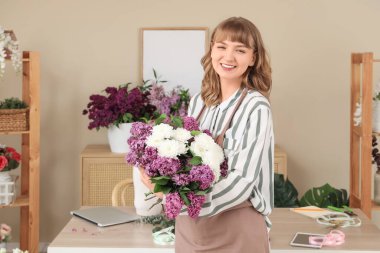 Çiçekçide çiçek buketi, leylak ve kasımpatı tutan kadın.