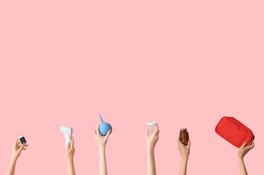 Eller lavman, ilk yardım çantası, haplar ve pembe arka planda termometre.