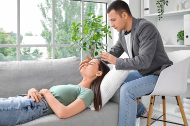 Psikolog muayenehanesinde hipnoz seansı sırasında kanepede yatan genç bir kadın.