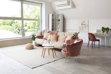 Yastıklı rahat kanepe, koltuk ve oturma odasının içinde çiçekler olan kahve masası.