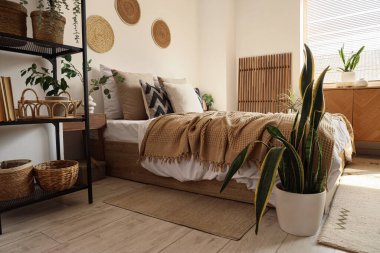 İçinde bitkiler, raf ünitesi ve katlanır ekran olan rahat bir yatak odası.