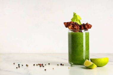 Beyaz arka planda domuz pastırması ve kerevizle süslenmiş bir bardak Bloody Mary kokteyli.