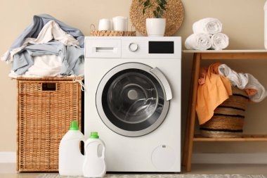 Çamaşır makinesi, çamaşır sepeti ve masası olan şık bir banyo.