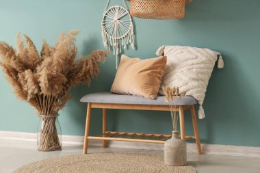 Gri bank, yastıklar ve vazo. Salonun içinde otlar var. Yakın plan.