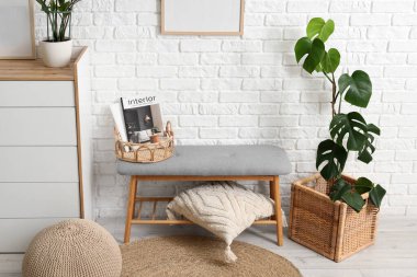 Rahat gri bir bank, çekmeceler ve yastıklar odanın içindeki beyaz tuğla duvarın yanında, yakın plan.