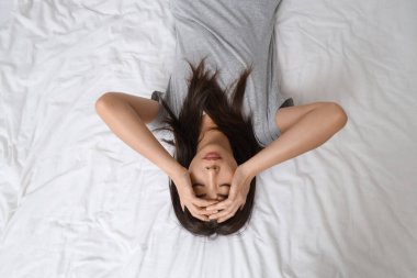 İntihara meyilli genç Asyalı kadın yatakta yatıyor.