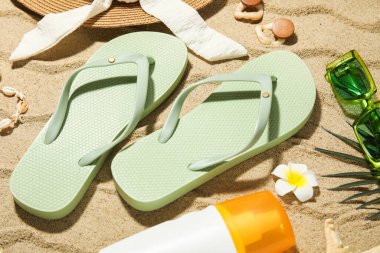 Arka planda plaj ayakkabıları, aksesuarları ve bir şişe güneş kremi olan kompozisyon, yakın plan.