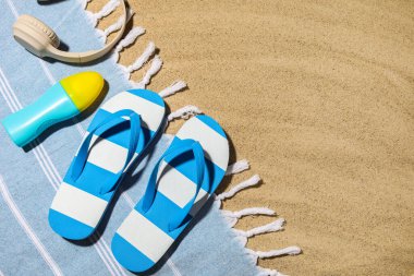 Arka planda plaj ayakkabıları, kulaklıklar ve bir şişe güneş kremi olan kompozisyon, yakın plan.