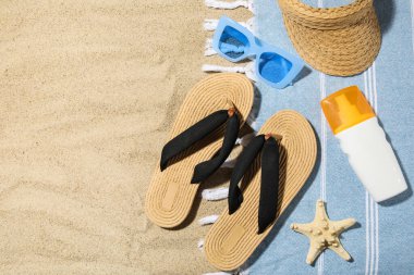 Arka planda plaj ayakkabıları, aksesuarları ve bir şişe güneş kremi olan kompozisyon, yakın plan.