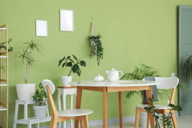 Çay seti ve yeşil bitkilerle dolu yemek masası.