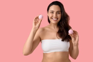 Pembe arka planda banyo bombaları olan güzel bir kadın.