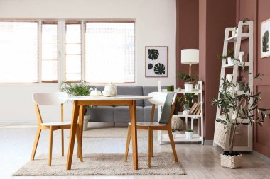 Oturma odasının içinde yeşil bitkiler, kanepe ve yemek masası.