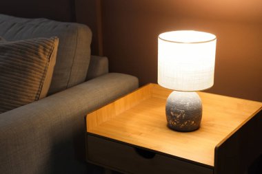 Karanlık oturma odasındaki masada parlayan lamba.