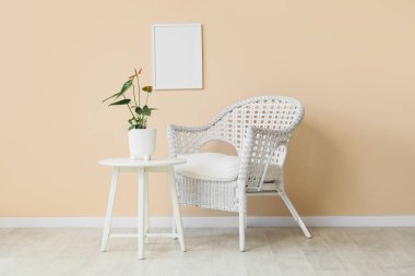 Masadaki güzel Anthurium çiçeği ve odadaki bej duvarın yanındaki koltuk.