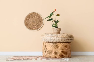 Odadaki bej duvarın yakınındaki rattan puf üzerinde güzel bir Anthurium çiçeği.