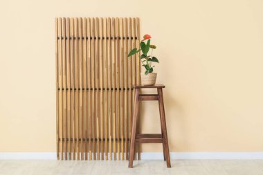 Masada güzel bir Anthurium çiçeği ve odada bej duvarın yanında katlanan bir ekran.