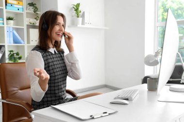 Ofiste konuşan kulaklıklı bayan teknik destek ajanı.