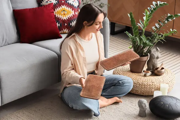 Sadhu tahtası olan genç bir kadın evdeki halıda oturuyor.